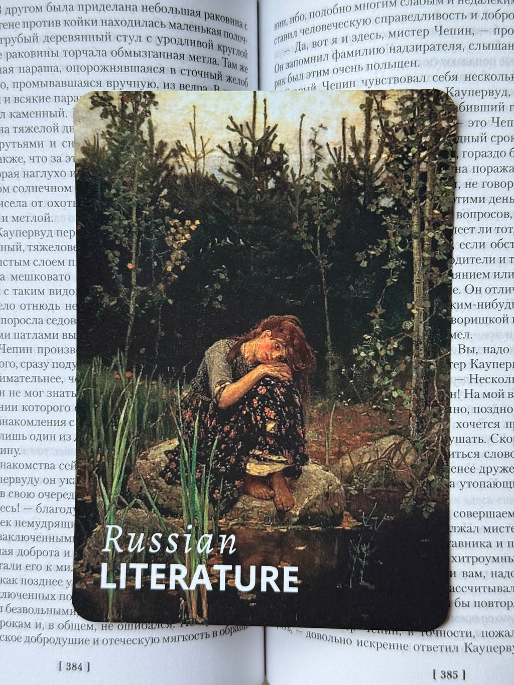 A rectangular book cover or bookmark featuring a dark, moody painting of a woman in a forest, with the text 'Russian LITERATURE' in white at the bottom, placed over an open book with printed text.