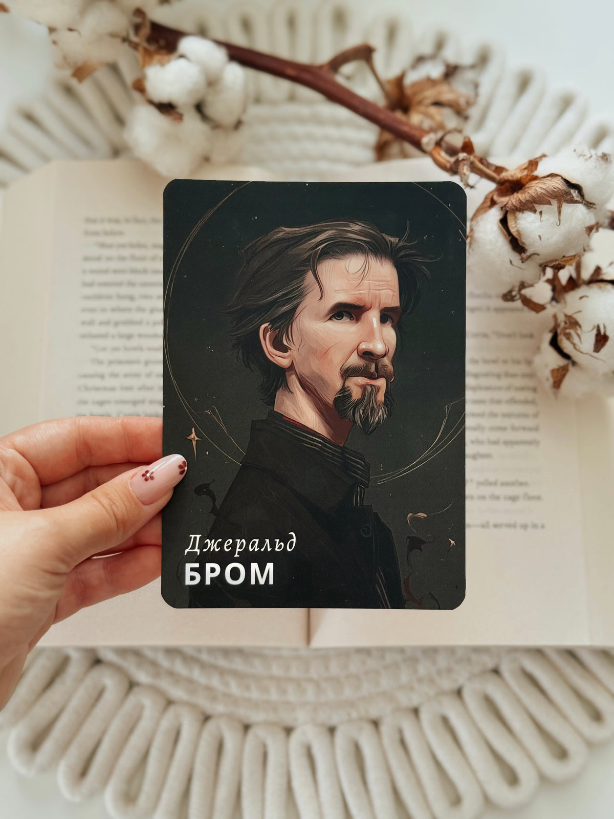 A hand holds a tarot card featuring a portrait of J.R.